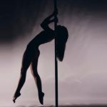 Frau Pole macht Shoulder Mount auf Pole Dance Stange